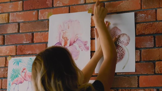 Painting hobby results. Talented artwork. Artist sticking drawings on the wall.