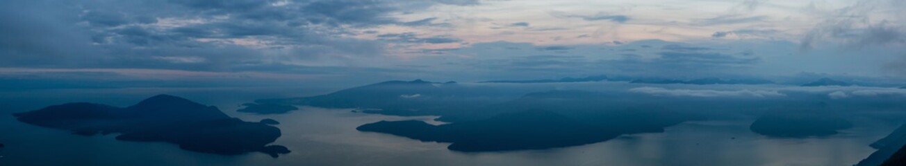 Beautiful Panoramic View of Canadian Mountain Landscape covered in clouds during a vibrant summer sunset. Taken on top of St Mark's Summit, West Vancouver, British Columbia, Canada.