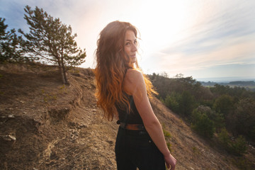 young woman in black. girl on the edge of the mountain happily watching back and smiling. Freedom, happiness, nature
