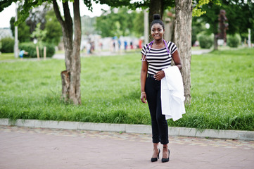 Young african american female doctor hold white coat on hand with a stethoscope posed outdoor.