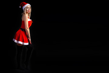 Young beautiful blonde girl in a sexy red Snow Maiden costume or Santa Claus on a black isolated background in the Christmas and New Year 2020 holidays with the place for text