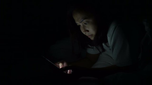 Asian woman playing game on smartphone in the bed at night,Thailand people,Addict social media	