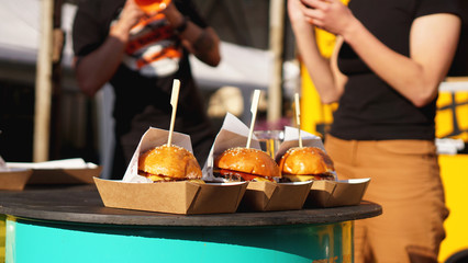 Beef burgers being served on food stall on open kitchen international food festival event of street...