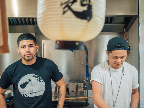 Young multiracial men cooking and serving Japanese dish ramen in Asian bistro