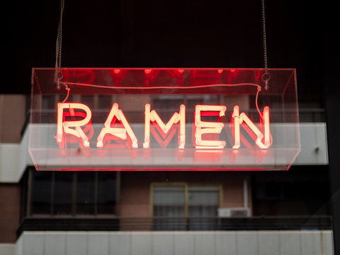 Illuminated signboard with restaurant name Ramen symbolizing traditional Japanese dish hanging outdoors