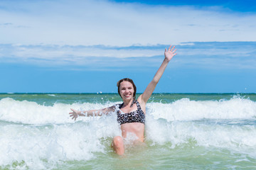 Fototapeta premium A joyful, contented middle-aged woman swims in the sea in waves.
