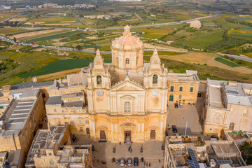 Fototapeta na wymiar St. Paul's Cathedral in the town of Mdina surrounded by a fortress narrow streets, aerial view.