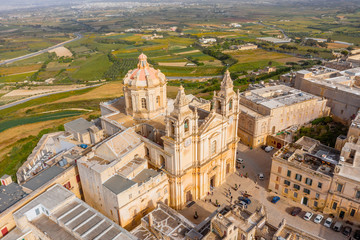 St. Paul's Cathedral in the town of Mdina surrounded by a fortress narrow streets, aerial view.