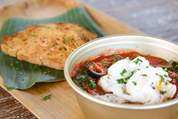Poached eggs in tomato sauce served with homemade black bread