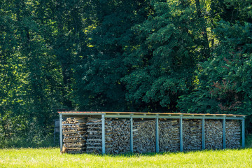 Brennholz Lager abgedeckt auf Wiese im Sommer © focus finder