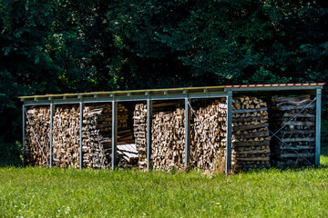 Brennholz Lager abgedeckt auf Wiese im Sommer