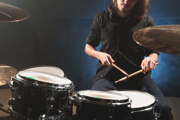 Close-up of a male drummer's hand holding drum sticks while sitting behind a drum set
