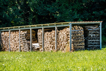 Brennholz Lager abgedeckt auf Wiese im Sommer © focus finder