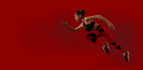 Fototapeta na wymiar Sporty woman running. Red background