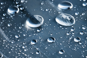 Close-up of raindrops of different sizes on the surface covered with cling film. Moisture weather and humidity concept