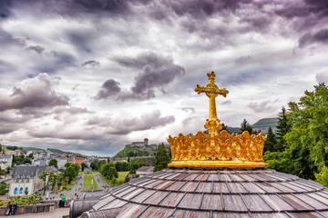 Christian gold cross on the roof of the Basilica of Our Lady of the Rosary in Lourdes, France