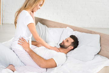 beautiful couple in pajamas hugging in bed at home