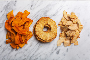 Apple, pineapple and mango chips on a table, top view