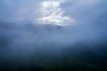 Montenegro, Dark rain clouds and fog hiding beautiful endless green nature landscape of tara river canyon from above a mountain top in the evening