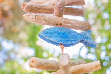 Wooden fish with park on background. Signboard of fish tavern, cafe, restaurant with food. Sign of faith. Fish sign and symbol background. Wooden fish hanging on the rope
