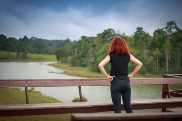 young woman is standing , looking at nature
