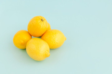 Pile of ripe yellow lemons on pale blue backgrounds.