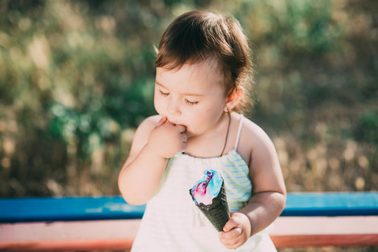 cute girl eating ice cream in a black horn of blue color, funny and beautiful counter light