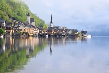 Fototapeta na wymiar Amazing Hallstatt village with beautiful lake and alps mountains on background. Unesco heritage. Austria landmark with historic cathedral and wooden houses on the lake. Romantic view 