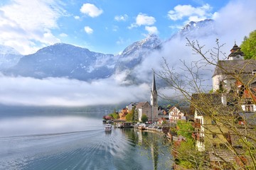 Naklejka premium Amazing Hallstatt village with beautiful lake and alps mountains on background. Unesco heritage. Austria landmark with historic cathedral and wooden houses on the lake. Romantic view 