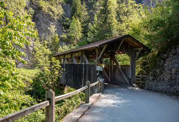 View of an old historic covered wooden bridge with high mountains in the background in the swiss alps