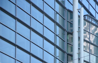 Sectional close up view of a modern high ride office building glass facade with some window reflections