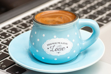 Turkish coffee inside blue cup on keyboard laptop at morning