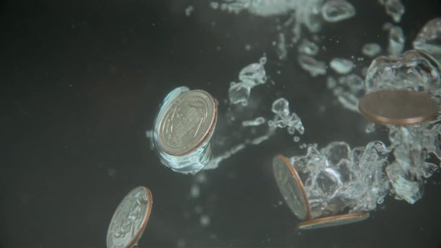 Air bubbles created from quarters falling into water slow motion