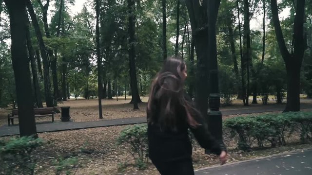 White handsom brown hair girl in tight black pants woman riding roller skates in park, during summer day