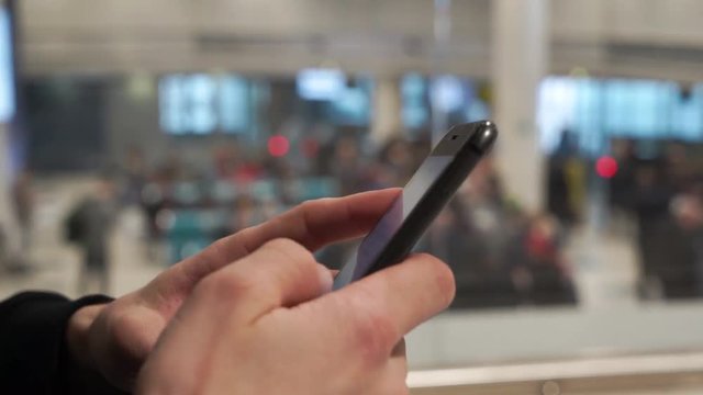 Airport traveler using cell phone in busy airport terminal