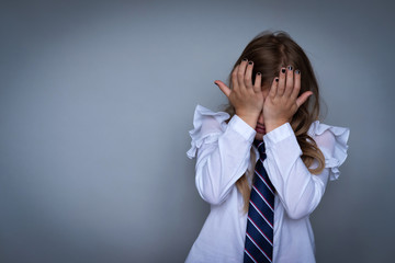 Small schoolgirl covering face, crying portrait. Preteen stressed, scared child hiding, wiping off...