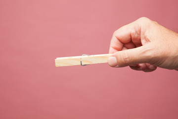 Pinzas de madera de tender la ropa, en la mano derecha de una persona adulta