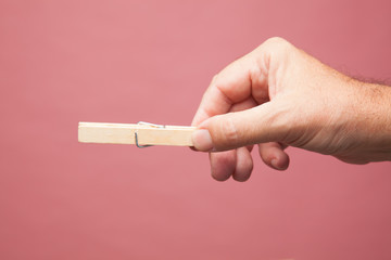 Mano sujetando unas pinzas de madera de las de extender la ropa, Pinzas abierta y cerrada.