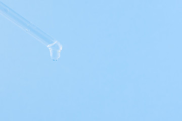 Serum for cosmetic procedures. Serum on a blue background. Cosmetic pipette with a drop. Minimalism. Close up