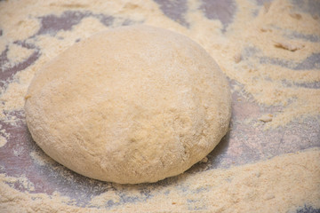 Fototapeta na wymiar Dough and flour on a wooden board close-up
