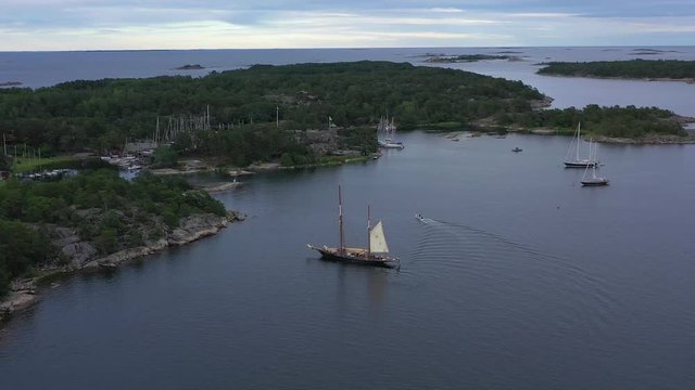 Wide rotating view of pirate style tall mast ship & yachts around Sandhamn island marina. High aerial orbit