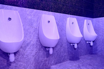 Urinals in the toilet on the wall hanging in a row.
