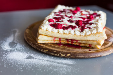 Puff pastry pie with curd and raspberry and powdered sugar on grey table