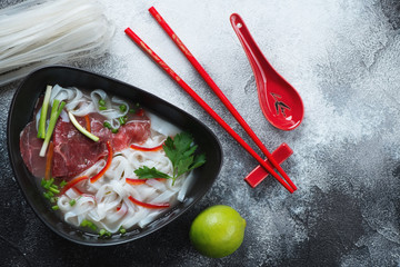 Pho bo soup with beef meat, flatlay with copy space on a grey stone background, horizontal shot
