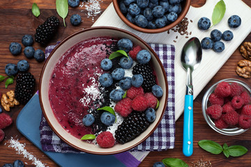 Healthy organic smoothie with blackberry and banana, decorated with raspberry, blueberry and coconut chips. Fashionable and healthy food from natural ingredients. Super food