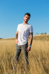 Attractive man with tattoos on his arms in a meadow