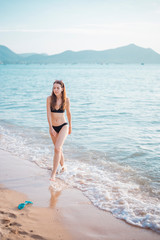 Beautiful woman in black bikini is walking from sea, summer concept