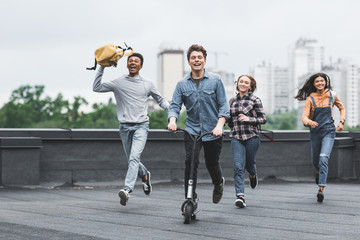 playful and smiling teenagers running on roof and riding scooter © LIGHTFIELD STUDIOS