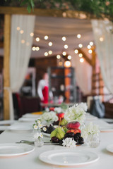 Wedding table setting. Festive table with white tablecloth. guests sit at the table. on the table are fruits, cheeses, glasses. cheese and wine tasting