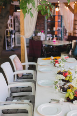 Wedding table setting. Festive table with white tablecloth. guests sit at the table. on the table are fruits, cheeses, glasses. cheese and wine tasting